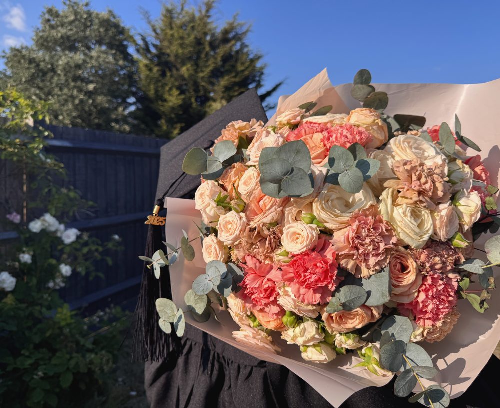 Graduate with a coral bouquet